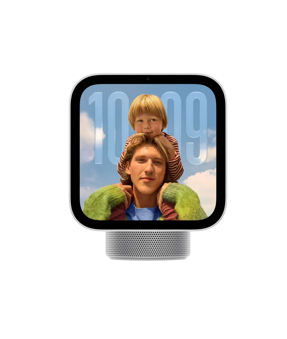 Apple HomeView, display with base, silver colour. Front exterior, square display, rounded corners, flat sides, black display bezel, centred top camera, cylindrical speaker base with circular perforations