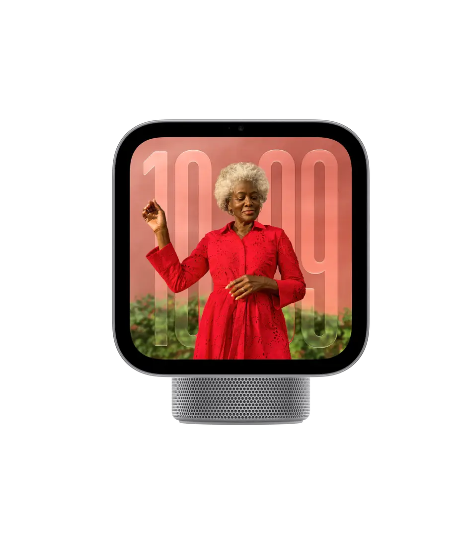 Apple HomeView, display with base, space grey. Front exterior, square display, rounded corners, flat sides, black display bezel, centred top camera, cylindrical speaker base with circular perforations