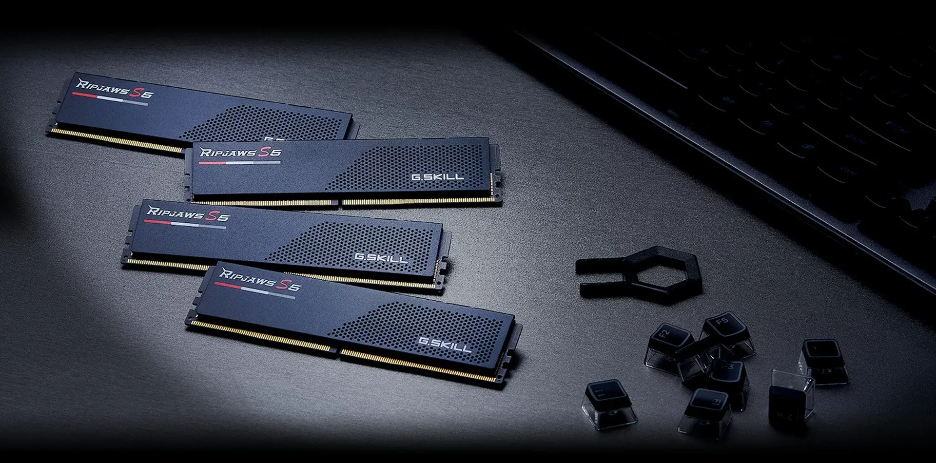 Four matte black G.SKILL Ripjaws S5 DDR5 modules lying on a dark surface