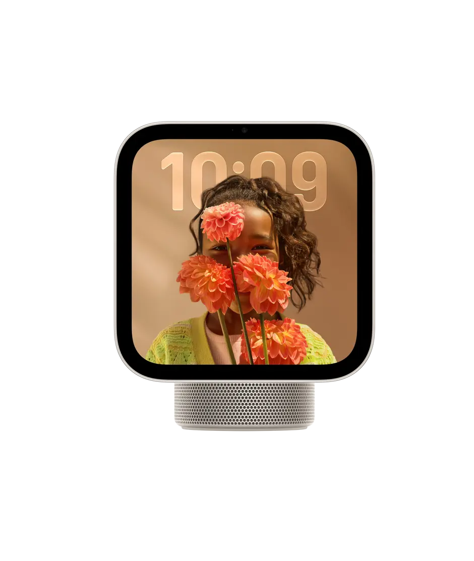Apple HomeView, display with base, starlight colour. Front exterior, square display, rounded corners, flat sides, black display bezel, centred top camera, cylindrical speaker base with circular perforations